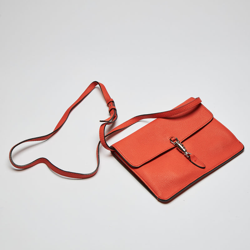 Excellent Pre-Loved Orange Pebbled Soft Leather Thin Crossbody Pouch with Removable Shoulder Strap and Silver Tone Hardware. (flat lay)