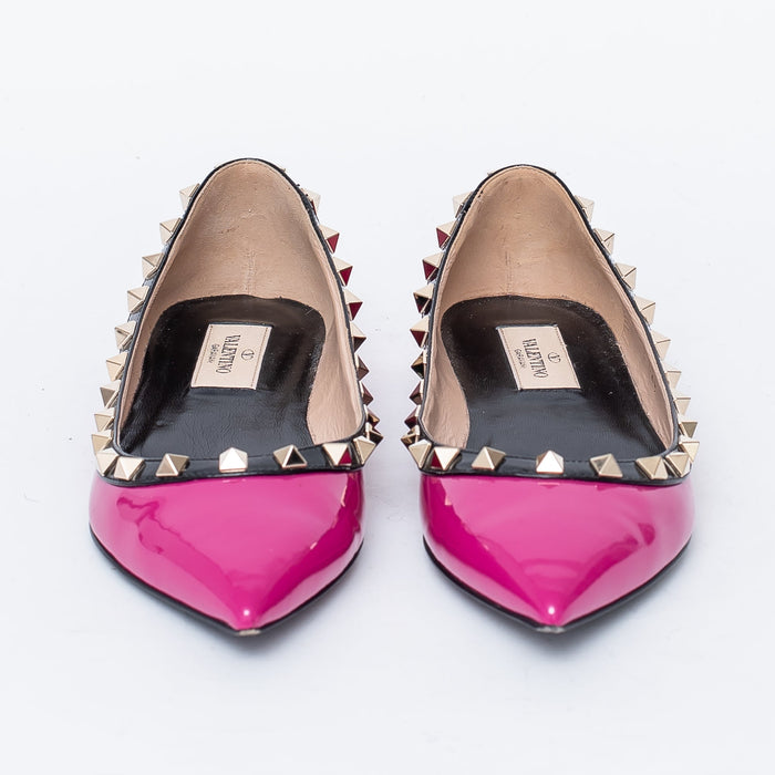neon pink point toe flats with black leather studded trim (front view)