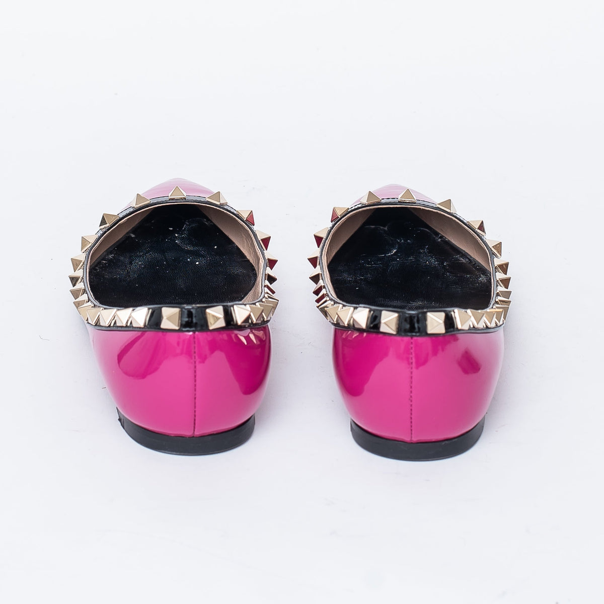 neon pink point toe flats with black leather studded trim (back view)