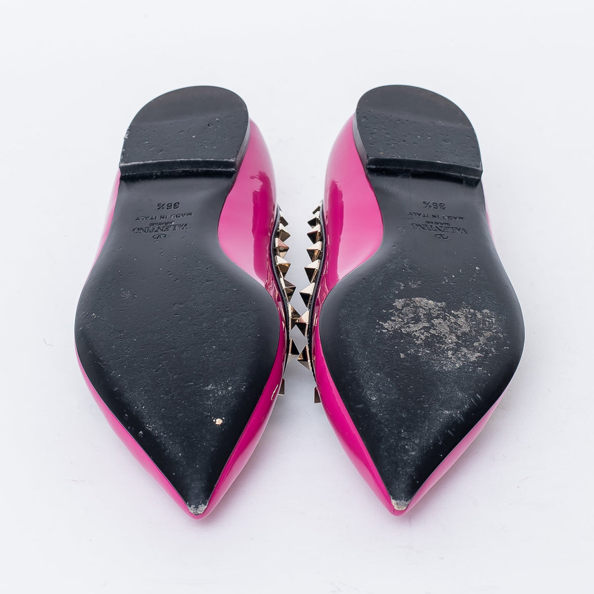 neon pink point toe flats with black leather studded trim (bottom view)